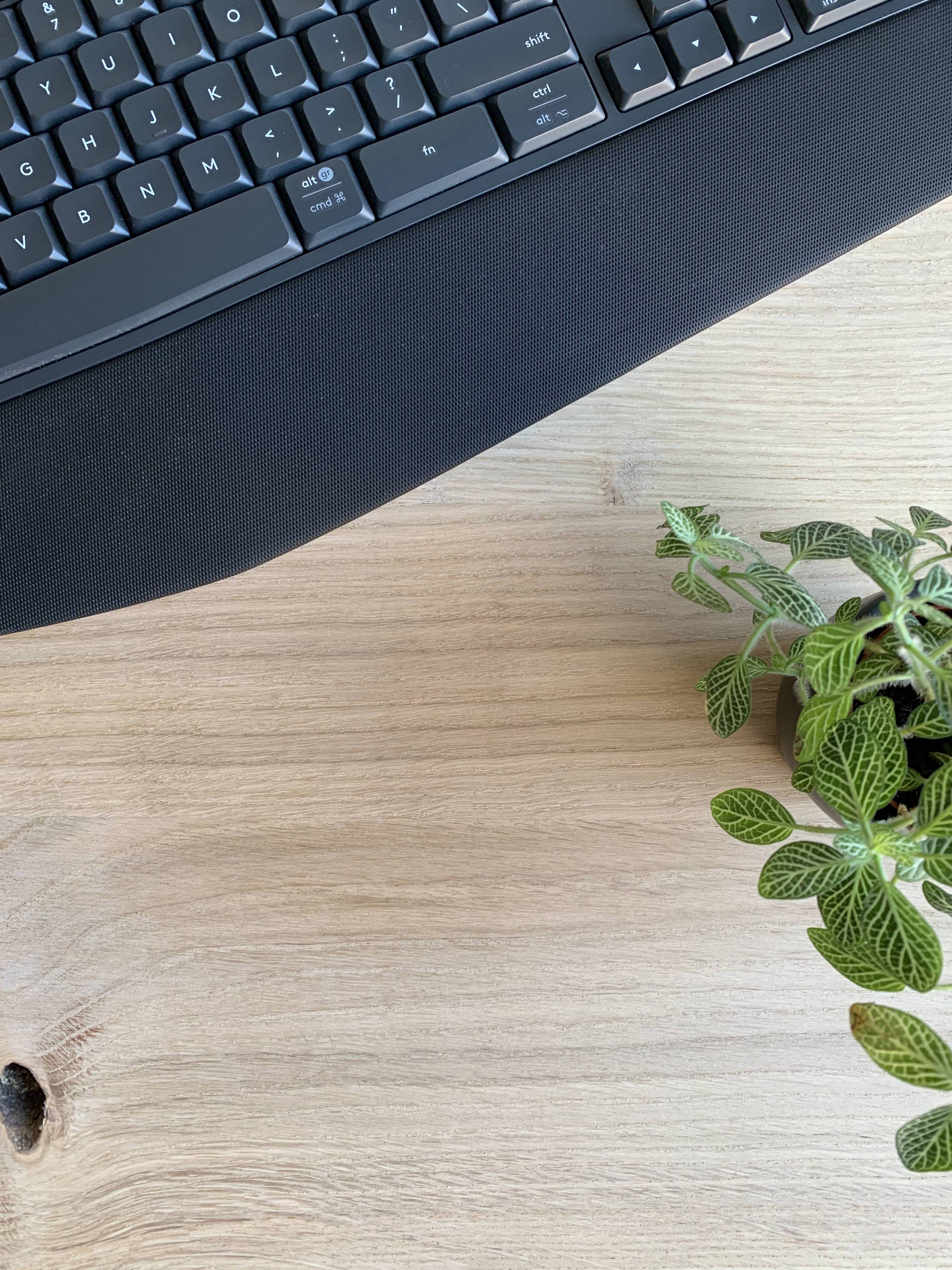 Blank eiken bureaublad met koffie, toetsenbord en plant